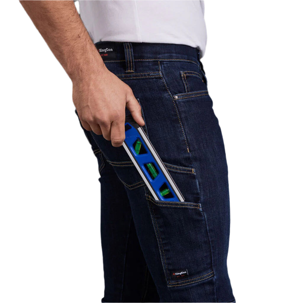 Person wearing dark blue jeans with a white shirt, holding a blue tool in a pocket.