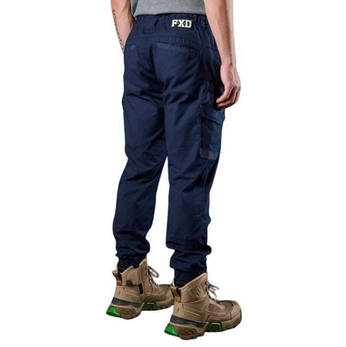 Person wearing navy cargo pants with 'FXD' branding on a white background