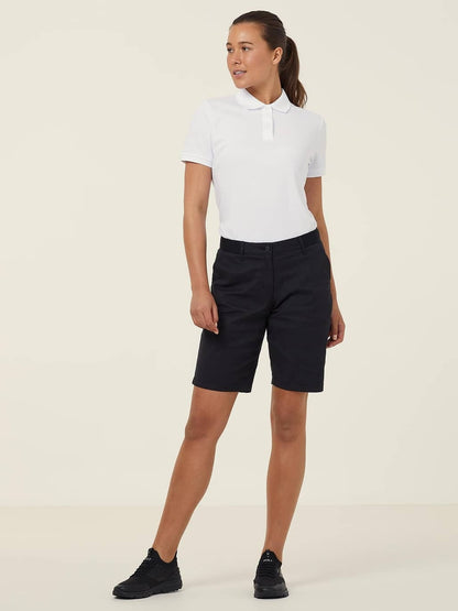 Woman wearing a white polo shirt and black shorts on a beige background