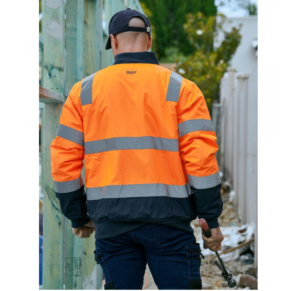 Person wearing an orange high-visibility jacket in an outdoor setting