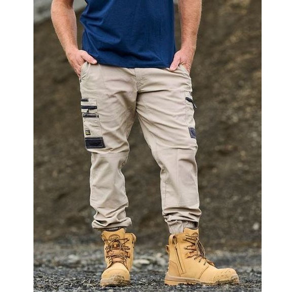 Person wearing beige cargo pants and tan work boots against a textured wall.