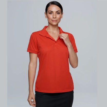 A woman wearing a red short-sleeved Aussie Pacific polo shirt with a knitted collar and cuffs.