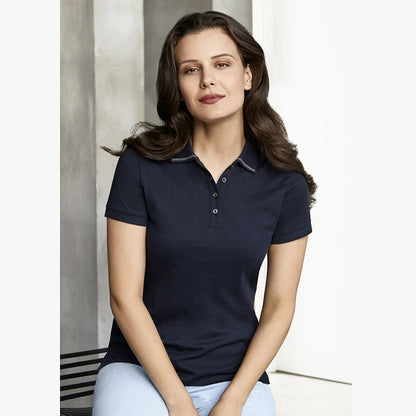 A woman sitting wearing a navy blue Biz Collection ladies' polo shirt with a collar and pearlized buttons.