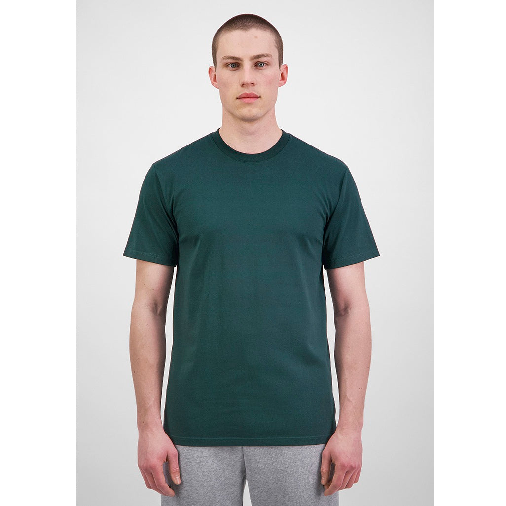 Man wearing a dark green t-shirt and gray pants on a white background