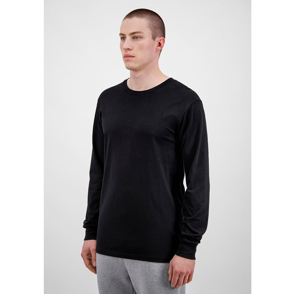 Man wearing a black long-sleeve shirt and gray pants on a white background