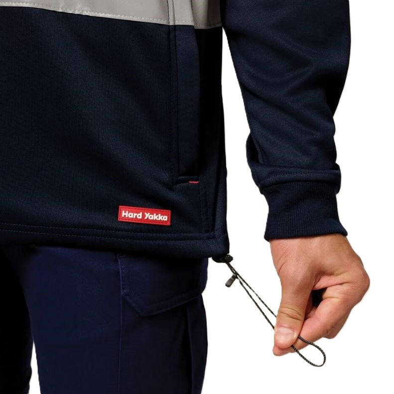 Person wearing a navy jacket with a visible brand logo, holding a metal tool against a white background.