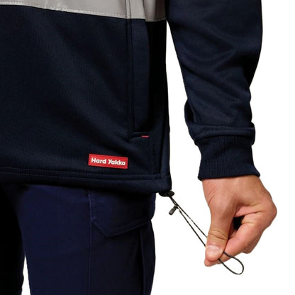 Person wearing a navy jacket with a visible brand logo, holding a metal tool against a white background.