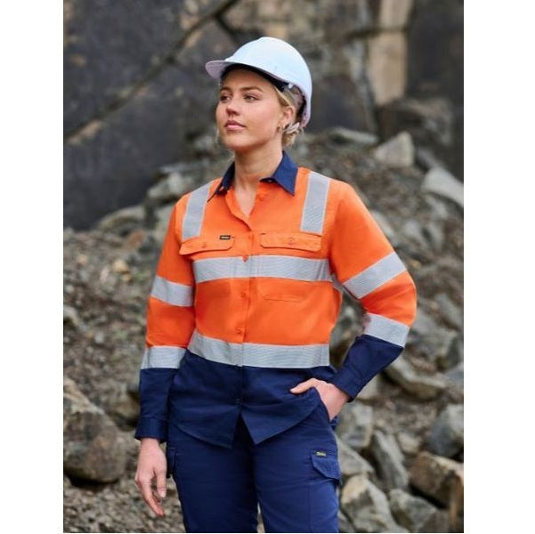 Person wearing an orange and blue work uniform with a hard hat in front of a rocky background