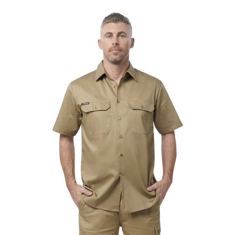 Man wearing a beige short-sleeve shirt with pockets on a white background