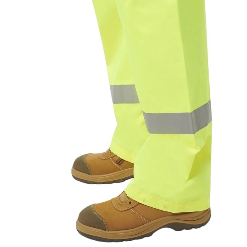 High-visibility yellow pants with reflective stripes and brown boots on a white background