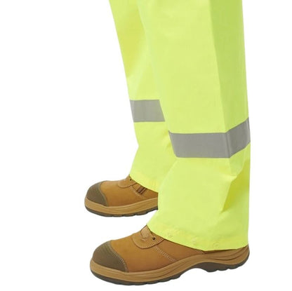 High-visibility yellow pants with reflective stripes and brown boots on a white background