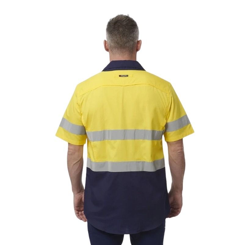 Person wearing a yellow and navy work shirt with reflective stripes on a white background