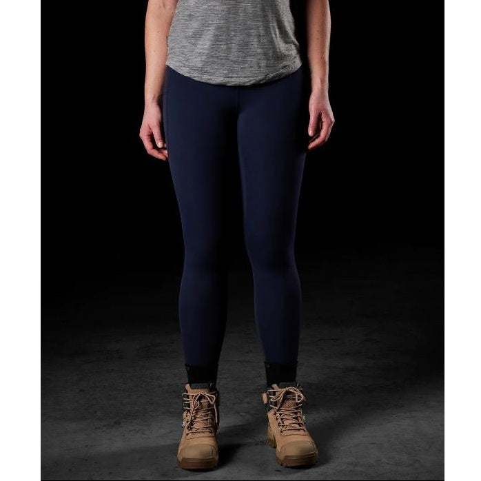 Person wearing navy leggings and brown boots on a dark background
