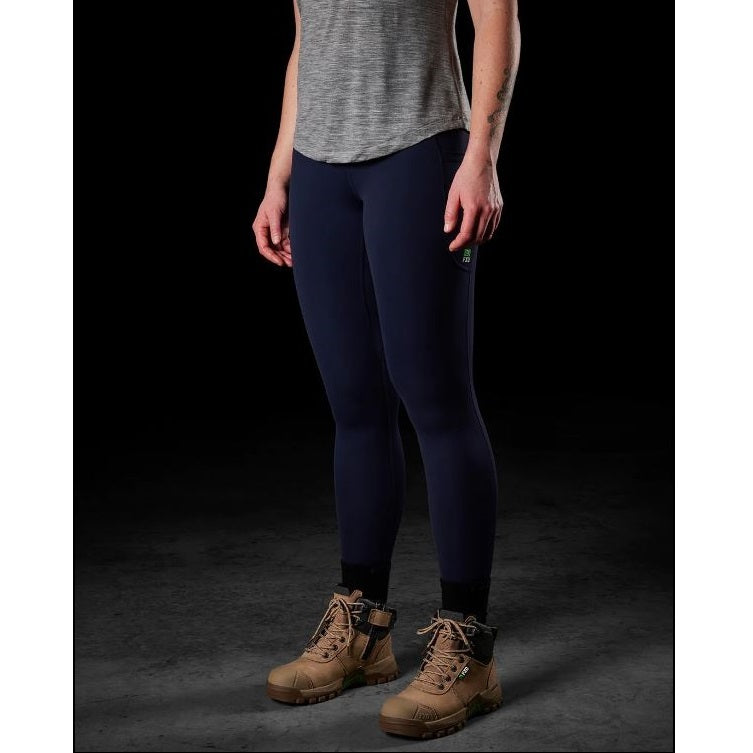 Person wearing navy leggings and brown boots on a dark background