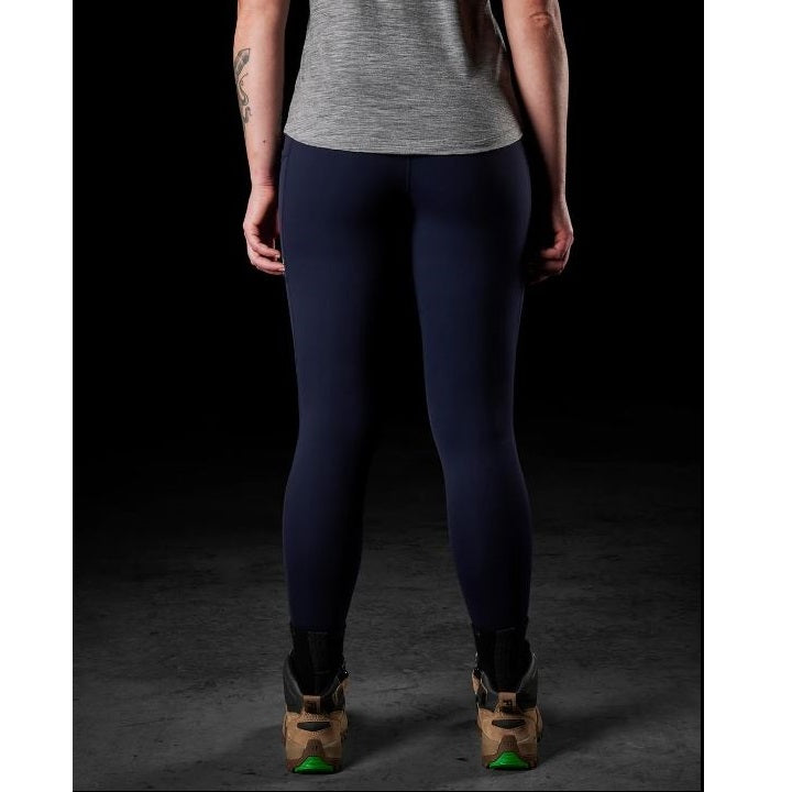 Person wearing navy leggings and a gray top on a black background