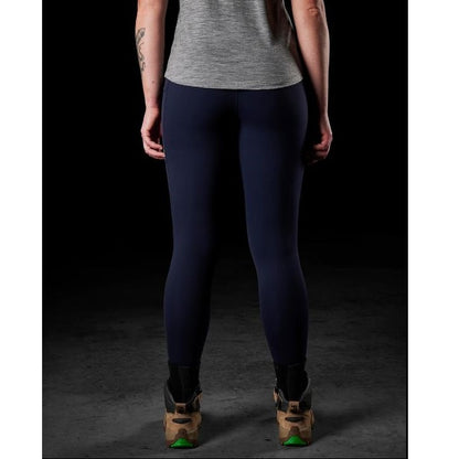 Person wearing navy leggings and a gray top on a black background