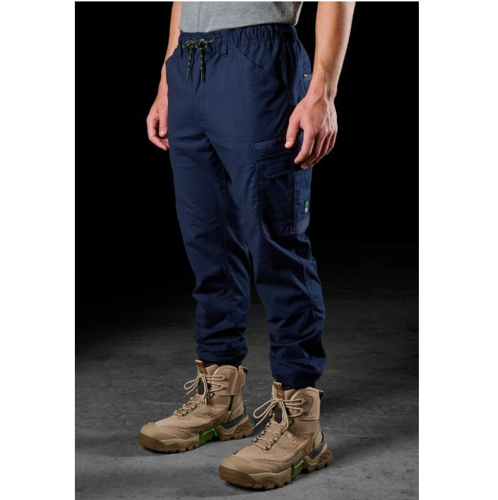 Person wearing navy cargo pants and tan boots on a dark background