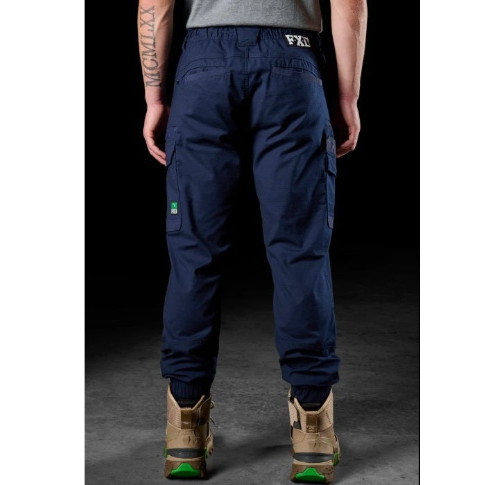 Person wearing navy cargo pants with visible FXD branding on a dark background