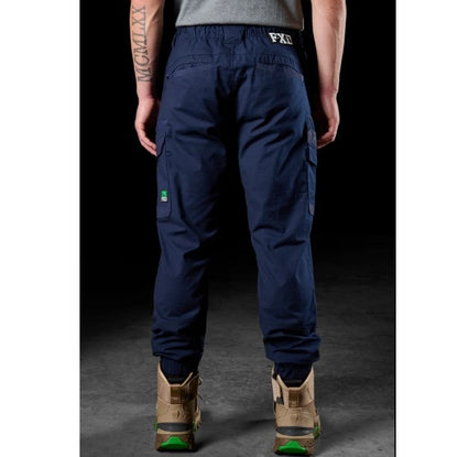 Person wearing navy cargo pants with visible FXD branding on a dark background
