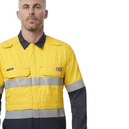 Person wearing a yellow and navy work jacket with reflective stripes on a white background