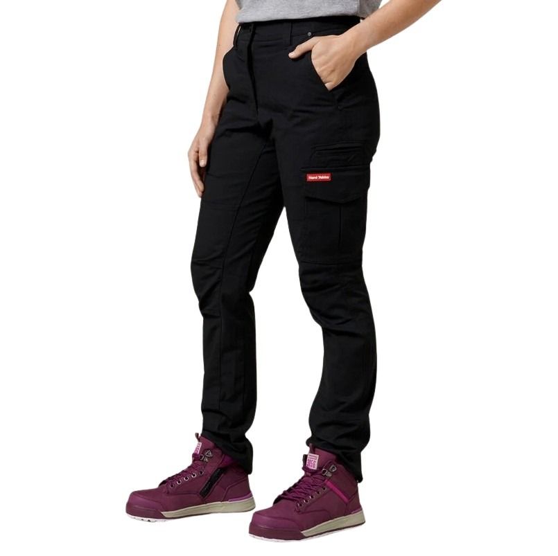 Person wearing black cargo pants with a red label and purple hiking boots on a white background
